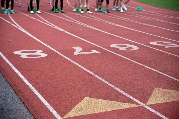 Biegacze na linii startowej sportowego toru wyścigowego z oznaczeniami pasa ruchu — Zdjęcie stockowe