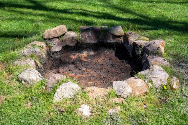 Rustic ancient outdoor stone circle fire pit in sunny grass background