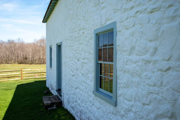 Side view of white colonial American stone cottage in rural landscape —  Fotos de Stock