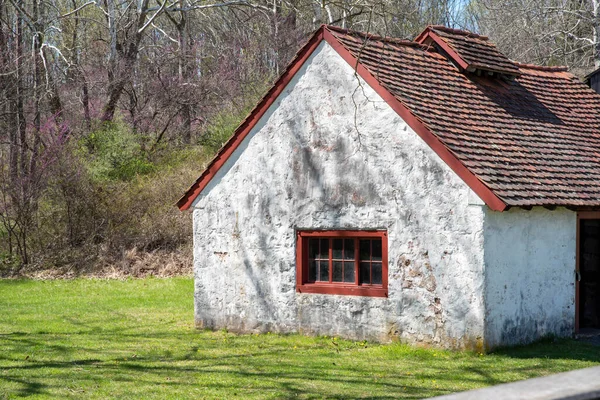Вид збоку на білий кам'яний котедж з антикварним червоним вікном в сільському пейзажі — стокове фото