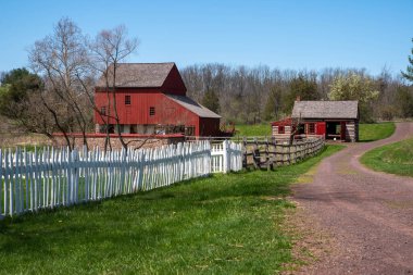 Idyllic Pennsylvania sahnesi, kırmızı ahşap ahır, ve bvcakground 'da ahşap kulübe ve beyaz çitli uzun bir patika. Kopya alanı olan ideal köy manzarası ve hiç kimse güneş ışığında vurulmamış..