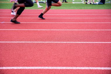 İki koşucu, açık hava spor pistinde doğal ışık altında fotokopi alanı ile birlikte beyaz şerit işaretleriyle yan yana yarışıyor..