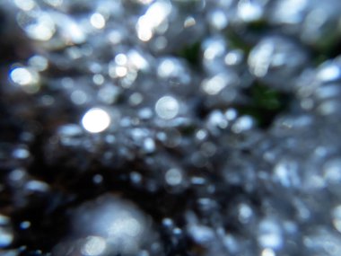 Siyah ve parıldayan beyaz ve gümüş kabarcıklar ile soyut odaklanmış arkaplan doğal ışıkta dinamik görüntüde hızla akıyor.