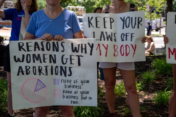 Philadelphia, PA USA 06-25-2022 Women hold feminist protest signs at a pro-choice reproductive freedom political rally at the National Constitution Center. Sign reads: KEEP YOUR LAWS OFF MY BODY