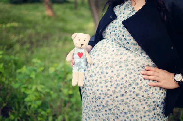 Woman expecting baby holding a cute teddy bear. — Stock Photo, Image