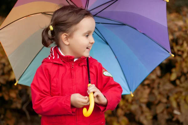 Criança com guarda-chuva arco-íris multicolorido ao ar livre — Fotografia de Stock