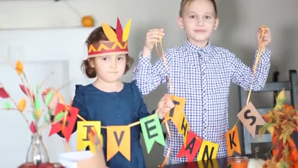 Niño sosteniendo guirnalda de papel con texto Dar las gracias. Niños decorando la sala de estar para celebrar el día de Acción de Gracias. — Vídeo de stock