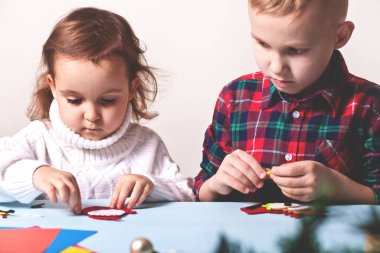 Çocuklar Noel ağacı ya da hediyeler için dekor yapıyorlar. Noel el yapımı diy projesi.