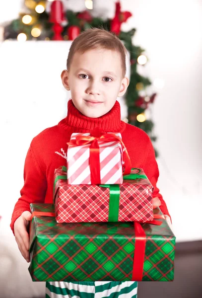 Дитячий хлопчик в червоному в'язаному светрі тримає різдвяні подарункові коробки в руках — стокове фото