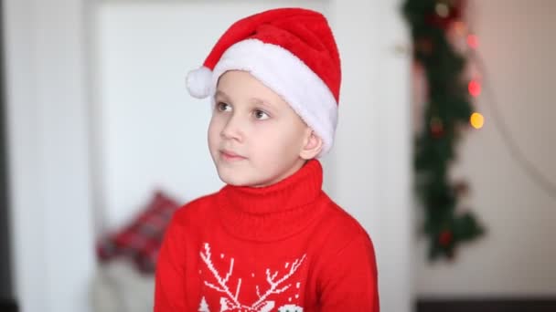 Kleine schattige jongen in grappige Santa cap en gebreide trui krijgen kerst geschenkdoos — Stockvideo