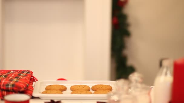 Chłopiec w czapce Santa biorąc spróbować ukraść ciasteczko ze stołu. — Wideo stockowe
