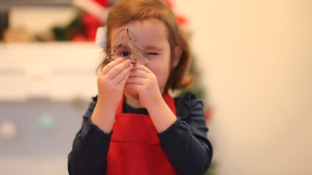 Klein schattig meisje dat thuis kerstkoekjes bakt. Kind spelen met koekjesschaar. — Stockvideo