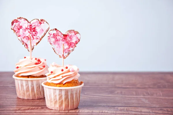 Valentine cupcakes creme de queijo cobertura decorada com pirulito coração doce no fundo de madeira — Fotografia de Stock