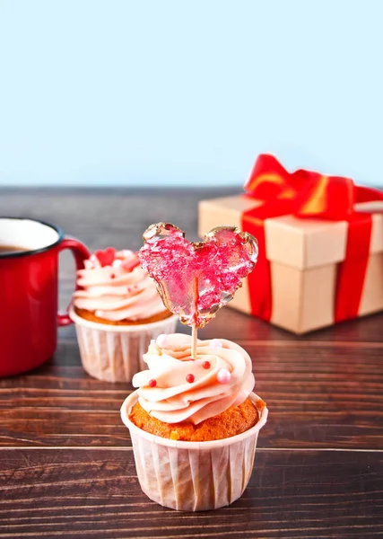 Cupcakes de San Valentín crema de queso glaseado decorado con paleta de caramelo corazón en el fondo de madera — Foto de Stock
