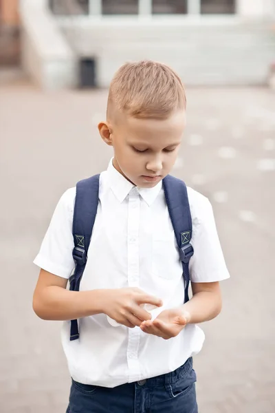 Menino usando desinfetante ou desinfetante spray para desinfetar as mãos na escola. Quarentena do vírus da coronária, conceito de prevenção de pandemias. — Fotografia de Stock