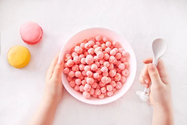 Skål med jordgubbar sockermajs bollar. Läckra och hälsosamma frukostflingor. Kid hand ta en sked och äta — Stockfoto