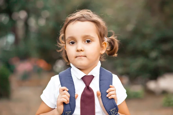 Klein schattig schoolmeisje in uniform met schooltas rugzak — Stockfoto