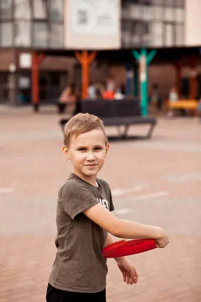 Chlapec se usmívá a hraje si na fisbee. Aktivní venkovní hra. — Stock fotografie