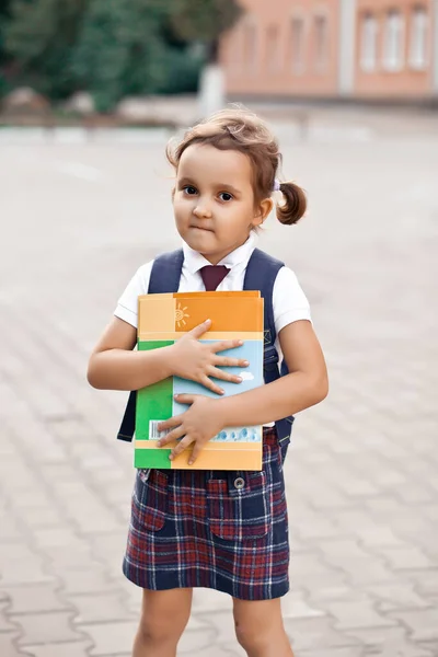 Klein schattig schoolmeisje in uniform met schooltas rugzak — Stockfoto