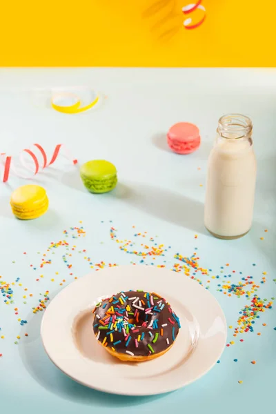 Delicioso donut com cobertura de chocolate com garrafa de leite e macaroons no fundo. Conceito de aniversário. — Fotografia de Stock