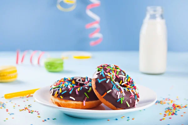 Deliciosos donuts com cobertura de chocolate com garrafa de leite e macaroons no fundo. Conceito de aniversário. — Fotografia de Stock