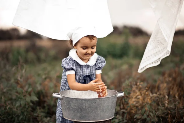 Menina bebê bonecas de lavagem em uma bacia de lata. Estilo retrô. — Fotografia de Stock