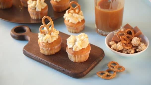 Vrouw hand versierd zelfgemaakte slagroom kaas cupcakes met karamel siroop — Stockvideo