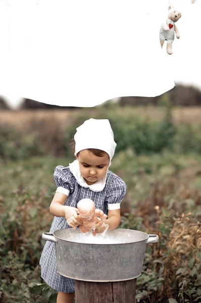 Menina bebê bonecas de lavagem em uma bacia de lata. Estilo retrô. — Fotografia de Stock