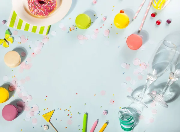 Essensrahmen mit leckerem Donut mit rosa Zuckerguss, Kerzenflasche Wein, Gläsern und Makronen auf blauem Hintergrund. Geburtstagskonzept. Ansicht von oben. Kopierraum. — Stockfoto