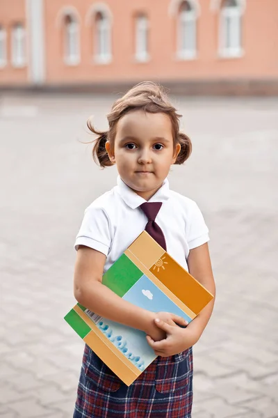 Pequena colegial bonito em uniforme com livros escolares — Fotografia de Stock