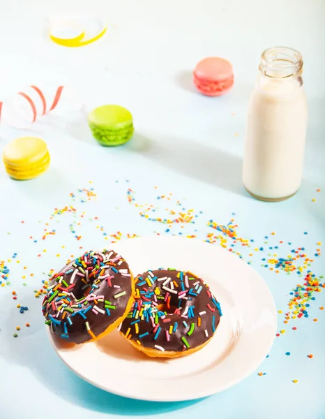 Deliciosos donuts com cobertura de chocolate e vela de aniversário com garrafa de leite e macaroons no fundo. — Fotografia de Stock