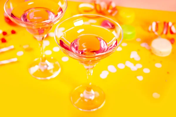 Glasögon av rosa cocktails med hjärta godis på gul bakgrund. Födelsedagsfest eller Alla hjärtans dag koncept. — Stockfoto