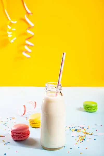Fles melk en macarons op de achtergrond. Verjaardagsconcept. — Stockfoto