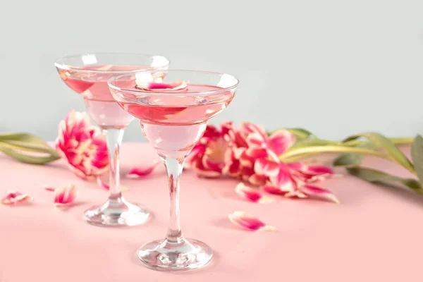 Glasögon av rosa cocktail med blommor och kronblad. Födelsedagsfest eller Alla hjärtans dag romatiska par koncept. — Stockfoto