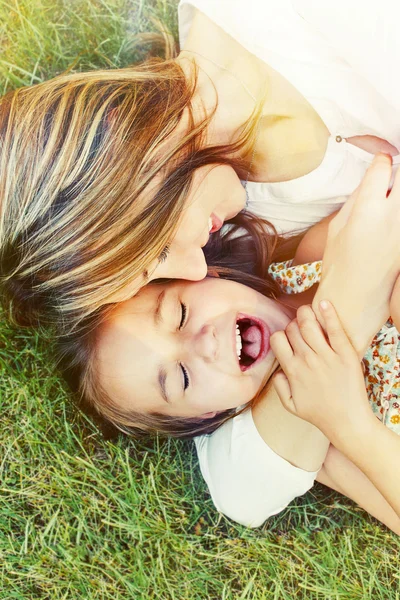 Счастливая маленькая девочка и ее мама весело проводят время на свежем воздухе на гра — стоковое фото