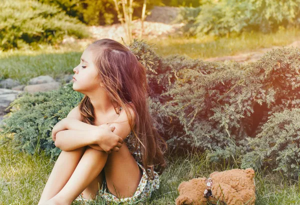 Молода маленька зіпсована дівчинка з іграшкою на відкритому повітрі в парку — стокове фото