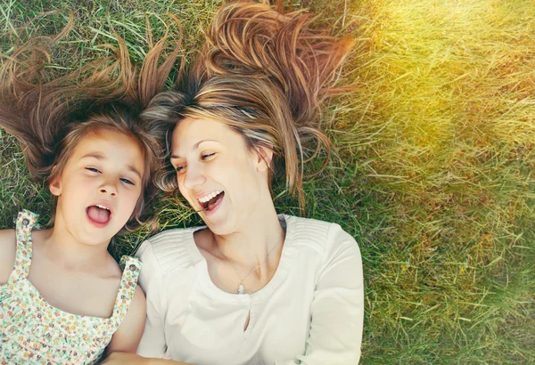 Süßes kleines Mädchen und ihre Mutter amüsieren sich im sonnigen Gras — Stockfoto