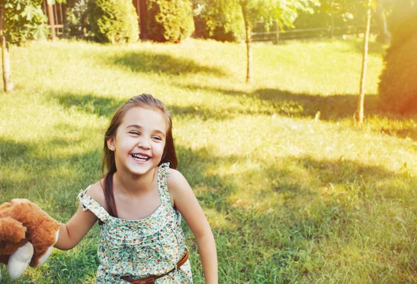 Счастливая улыбающаяся маленькая девочка, играющая с игрушкой в саду — стоковое фото
