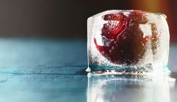 Fryst läckra röda körsbär i is på marinblå bakgrund — Stockfoto