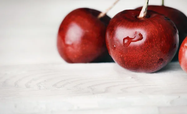 Ripe delicious cherries on white wooden table with water drops m — Stock Photo, Image