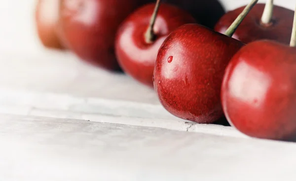 Cerezas maduras dulces sobre mesa de madera blanca con gotas de agua macro — Foto de Stock