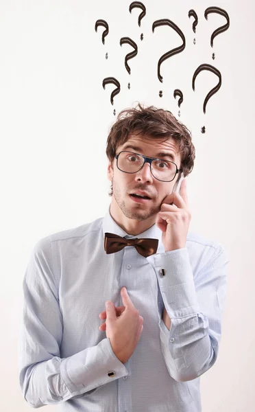 Amazed man with questioning expression and question marks above — Stock Photo, Image