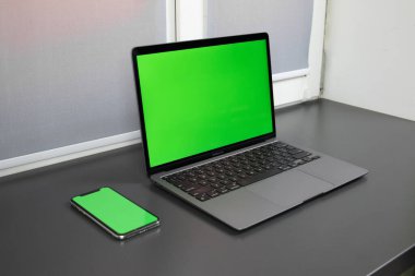 MacBook on a picture. MacBook keyboard. Phone next to laptop. iPhone and MacBook with green screen mock-up.