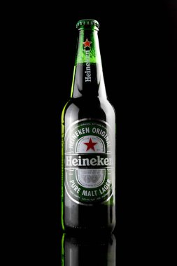 Bottle of Heineken beer on black background. Heineken logo on the bottle. Bottle on a glass table.