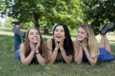 Kızlar çimlere uzanıyorlar. Kızlar parkta birlikte dinleniyorlardı. Ergenlerin hayatındaki mutluluklar. Yaz tatili.