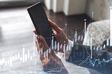 Elinde akıllı bir telefon tutan ve doğru yatırım çözümlerine ulaşmak için borsayı araştıran bir kadın tüccar. İnternet ticareti ve zenginlik yönetimi kavramı. Hologram Forex çizelgesi.