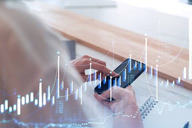 Elinde akıllı bir telefon tutan ve doğru yatırım çözümlerine ulaşmak için borsayı araştıran bir kadın tüccar. İnternet ticareti ve zenginlik yönetimi kavramı. Hologram Forex çizelgesi.