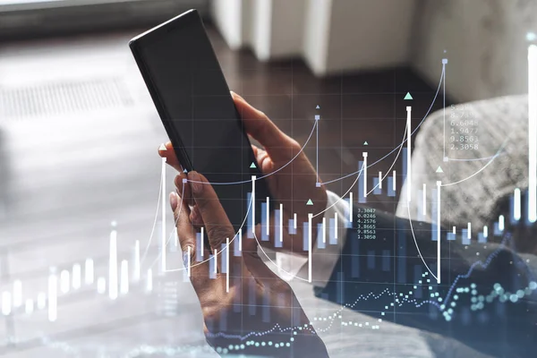 Elinde akıllı bir telefon tutan ve doğru yatırım çözümlerine ulaşmak için borsayı araştıran bir kadın tüccar. İnternet ticareti ve zenginlik yönetimi kavramı. Hologram Forex çizelgesi.