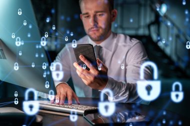 Sıradan giyinen bir iş adamı müşterileri gizli bilgilerini korumak için akıllı telefon kullanarak siber güvenliği kontrol ediyor. IT hologramı, modern ofis arkaplanının üzerine gece vakti simge kilitler.