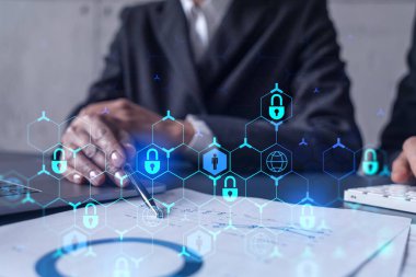 Uluslararası şirketin siber güvenliğini sağlamak için projede çalışan iki iş adamı ve kadın. Hologram simgelerini dokümanlarla masaya kilitle. Resmi kıyafet. Çalışma Alanı.